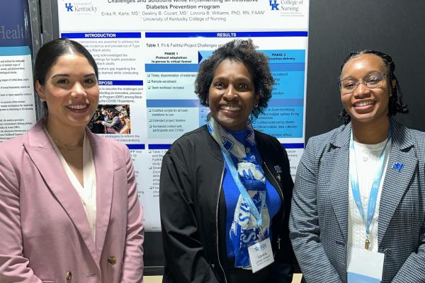 Three people standing in front of a research poster. 