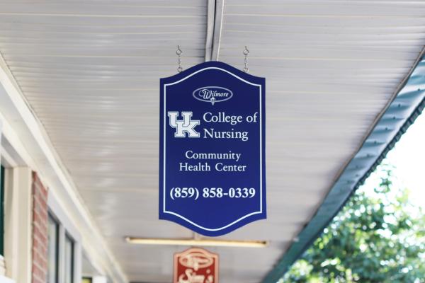 A blue hanging sign that says "UK College of Nursing Community Health Center (859) 858-0339."