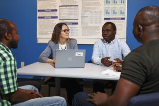 Woman sitting at a table with laptop open having a conversation with students