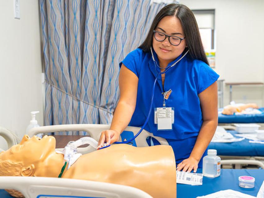 Student using stethoscope on simulation manequin.
