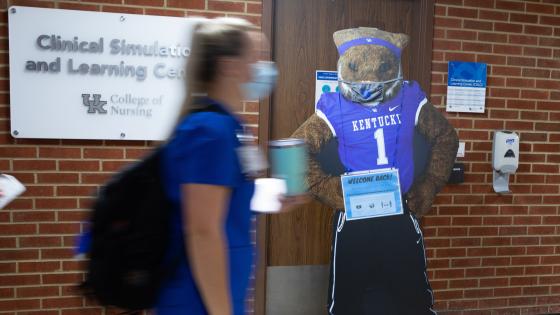 Student walking past the Clinical Simulation & Learning Center in the College of Nursing building. 