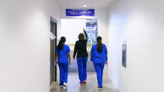 Candid image of Dr. Feld and students walking under nursing banner.