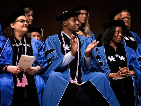 3 graduate students seated at the College of Nursing graduation ceremony. 