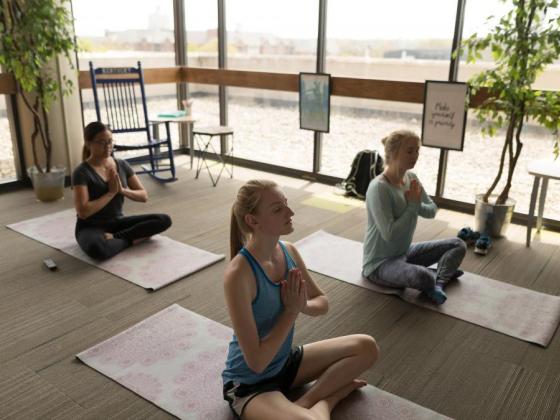 Three people meditating on yoga mats. 