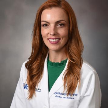 half body portrait of a woman with red hair and green shirt wearing a white doctor coat 