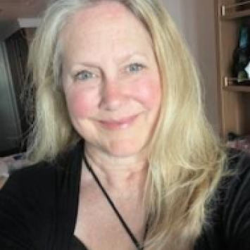 Woman with long blonde hair and black shirt smiles at camera.