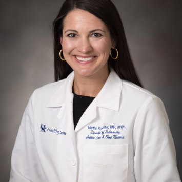 A woman smiling wearing a whitecoat.