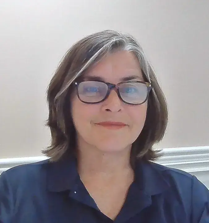 A headshot photo of a woman with glasses.