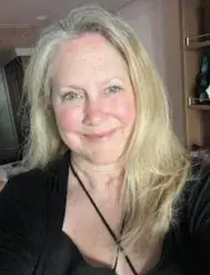 Woman with long blonde hair and black shirt smiles at camera.